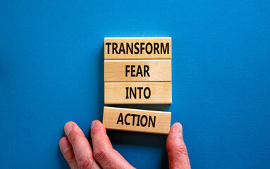 Transform fear into action symbol. Businessman holds wooden blocks with words 'Transform fear into action'. Beautiful blue background, copy space. Business, transform fear into action concept.