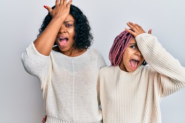 Beautiful african american mother and daughter wearing casual clothes and hugging surprised with hand on head for mistake, remember error. forgot, bad memory concept.