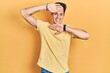 © Krakenimages.com - Young hispanic man wearing casual yellow t shirt smiling cheerful playing peek a boo with hands showing face. surprised and exited