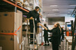 © Maskot - Male and female coworker holding package at logistics warehouse