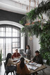 © Seventyfour - Vertical high angle portrait of diverse group of business people meeting at table in modern office interior decorated by plants, copy space