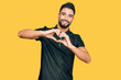 © Krakenimages.com - Young man with beard wearing sportswear smiling in love doing heart symbol shape with hands. romantic concept.