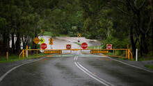 Bright Yellow And Red Stop Signs Warning Motorists That The Road Is Closed And Flooded. Youngs Crossing, Petrie, Queensland, Australia.
