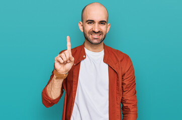 Young hispanic man wearing casual clothes showing and pointing up with finger number one while smiling confident and happy.