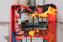 Burning Switchboard From Overload Or Short Circuit On Wall Close-up. Circuit Breakers On Fire From Overheating Due To Poor Connection Or Poor Quality Wires. Faulty Home Wiring Concept