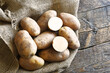 A top view image of several organic russet potatoes on a burlap sack. 