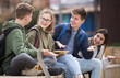 © JackF - Smiling cheerful teenagers talking with each other sitting on stairs on city street