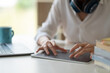 © Natee Meepian - Close up of female worker working from home with digital tablet, laptop and headphone in home office room.