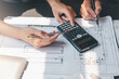 © amnaj - Architect man calculated the drafting using the blueprint calculator at the meeting.