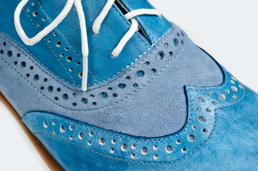 Blue imitation leather shoes laced with white laces. Close-up shot.