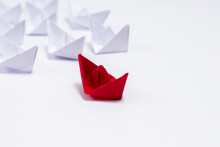 A Red Paper Boat With White Boats Following It In Leadership Concept.