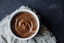 homemade chocolate pudding in white porcelain plate on dark background. homemade recipes for children. food content. chocolate paste texture . selective focus