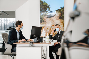 Sticker - Mid unshaven manager working with mature customer in car showroom