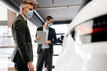 Sticker - Mid white manager in face mask showing car to customer in showroom