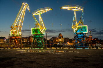 Wall Mural - Illuminated old port cranes on a boulevard in Szczecin City at night