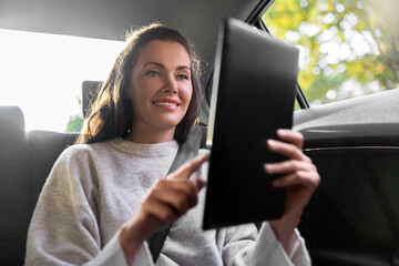 Wall Mural - smiling woman in taxi car using tablet pc computer