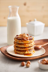 Wall Mural - Sweet pancake breakfast with milk and hazelnuts on a wooden utensils and wooden background