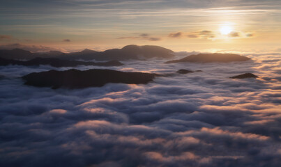 Wall Mural - sunset hidden behind clouds and fog over hills, bright yellow sun on colorful cloudscape, blue viole