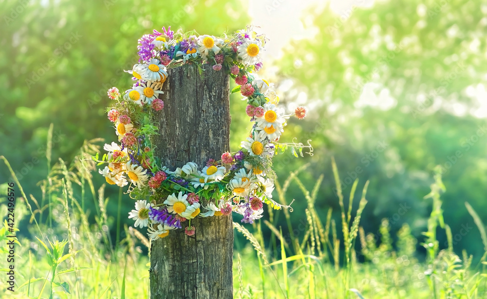 rustic wildflowers wreath on sunny meadow. Summer Solstice Day, Midsummer concept. floral traditional decor. pagan witch traditions, wiccan symbol and rituals - obrazy, fototapety, plakaty 