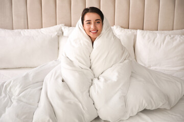 Poster - Beautiful young woman wrapped with soft blanket relaxing on bed at home