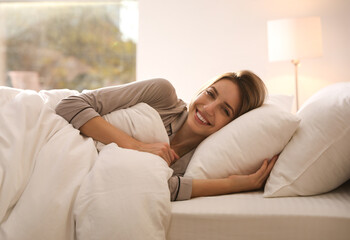 Poster - Cheerful woman under warm white blanket lying in bed indoors