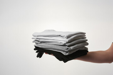 Wall Mural - Male hand holding stock of basic T-shirts against grey background