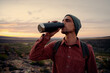© StratfordProductions - Young male hiker wearing backpack and cap drinking water standing on mountain