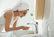 © New Africa - Happy young woman washing face in bathroom
