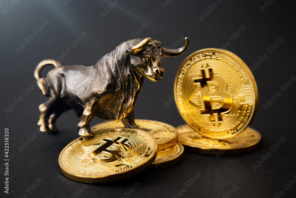Bull figurine standing on bitcoins, concept of cryptocurrencies