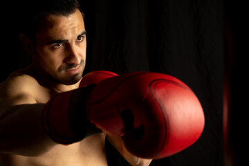 athlete man training with boxing gloves on black background