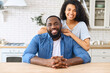 © Vadim Pastuh - Portrait of African-American couple in love in the kitchen at home, a beautiful biracial woman hugs the shoulders of handsome black man, they look at the camera and smile spending time at home