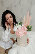 © Natalia - brunette girl in a white shirt sits next to a bouquet of flowers