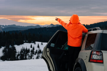 person in car on winter mountain at sunset