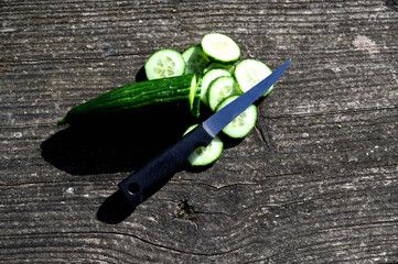 Sticker - sliced cucumber and a knife outdoor on a wooden table