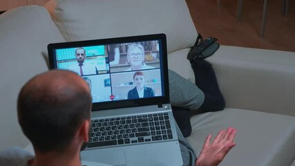 Poster - Back shot of tired man lying on sofa while chatting with teammates during business videocall conference use laptop computer. Caucasian male using modern technology wireless late at night in kitchen