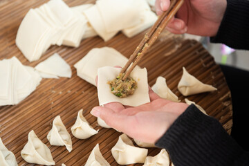 Chopsticks sandwich the meat into the dumpling wrapper to make dumplings