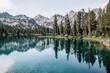 Beautiful blue crystal clear waters and mirrored lake reflections of pine trees and the surrounding Sawtooth Mountain Range on Alice Lake, in the Sawtooth National Recreation Area, Idaho, USA. 