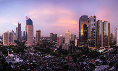 Wall Mural - Stunning sunset over Jakarta skyline where modern office and condominium towers contrasts with traditional village, called Kampung, in Indonesia capital city