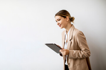 Wall Mural - Young woman holding digital tablet by the white wall in modern office