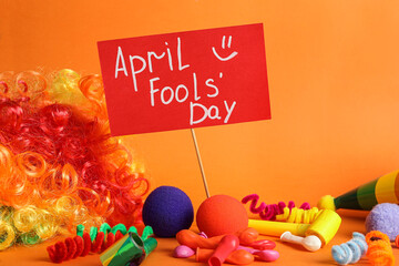 Wall Mural - Sign with phrase Happy Fools' Day and clown's accessories on orange background