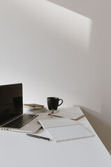 Wall Mural - Minimalist home office desk workspace. Laptop on table with coffee cup, paper sheet, stationery against white wall. Work, business background.