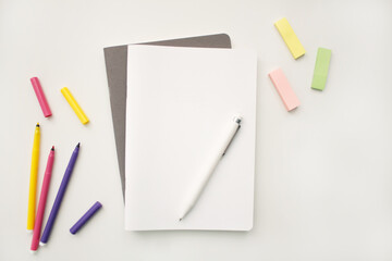 Wall Mural - Notepad on a white background with colored pencils and felt-tip pens, rulers and scissors. The notebook lies on a plain background with space for writing. Composition of writing to-dos for the day.
