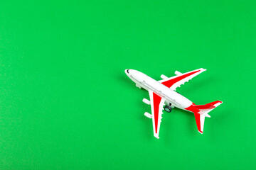 Wall Mural - plastic model of an airplane with red wings. tourism and travel concept. green background top view