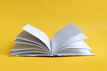 Wall Mural - open book on a yellow background. The book lies on a plain background with space for writing. Composition of a reading person.