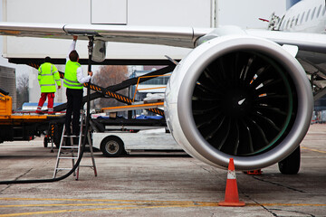 Refueling the plane. Airport handling. A male worker on the stairs connects the hose. Service, luggage loading. Preparing the plane for flight.