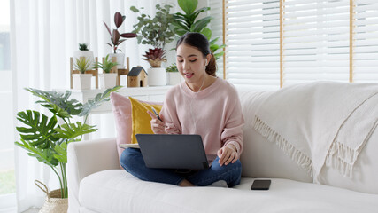 Wall Mural - Young attractive business asian woman talking about sale report in video call conference on notebook computer online meeting in working from home, Working remotely and Social isolation concept.