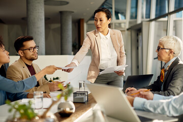 asian executive director shares reports to her business team during meeting in office.