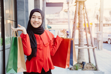 Arab Muslim young woman in veil hijab clothes holding shopping bags at city metro walking street.