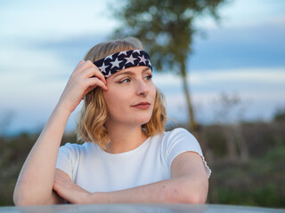 Portrait of a beautiful Caucasian woman with a nose ring and a trendy bandana at a park