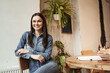 © LIGHTFIELD STUDIOS - cheerful young woman smiling and looking at camera near table with smartphone and notebook